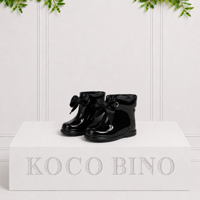 Glossy black girls' gumboots with elegant satin ribbon bows, offering waterproof comfort and timeless style for wet weather.