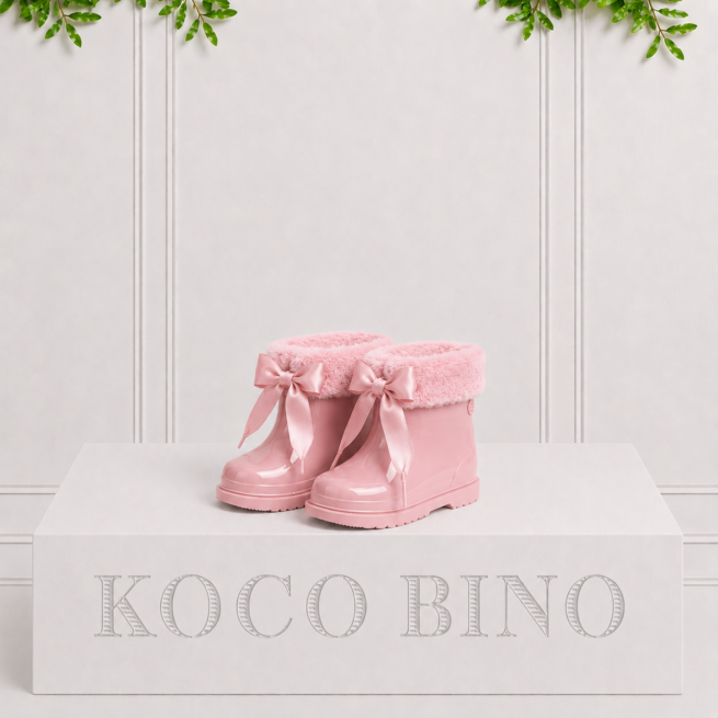 Glossy pink children's rain boots with fluffy faux fur lining and satin bows, adding warmth and charm to rainy day adventures.