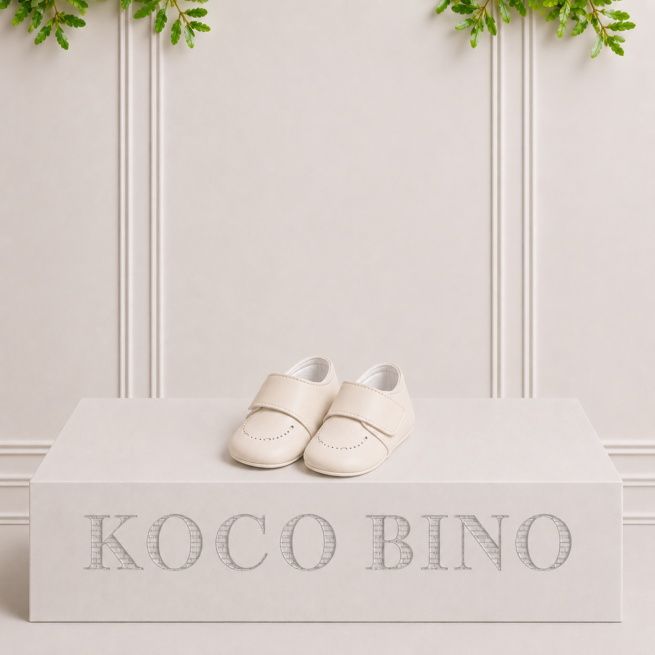 Classic Kai baby shoes in ivory leather with a timeless design, beautifully presented on a Koco Bino podium in studio.