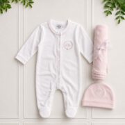 Baby girl gift set with a white babygrow, pink blanket and matching hat displayed on an elegant white background with greenery.