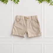 Boys stone cotton shorts with classic front pockets, belt loops and turned-up cuffs, displayed flat against a white panelled background.