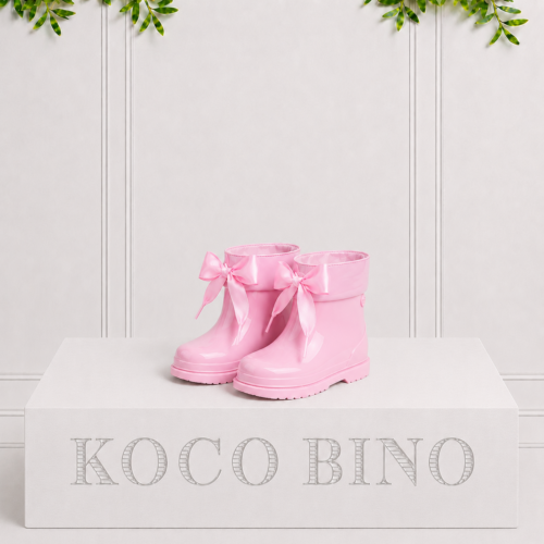 Glossy pink children's rain boots with satin ribbon bows, adding a playful touch while keeping little feet dry on rainy days.