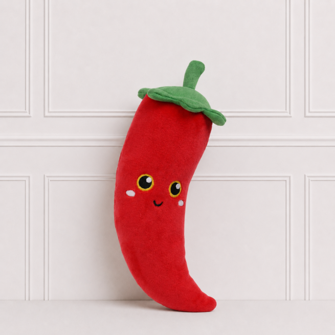 Soft red chilli plush toy with embroidered smiling face, bright eyes and green leafy top, displayed on a neutral background for nursery décor.