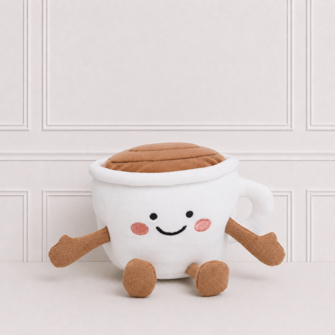 Soft white choco cup plush toy with smiling embroidered face, chocolate topping, little arms and legs on a neutral background for nursery décor.