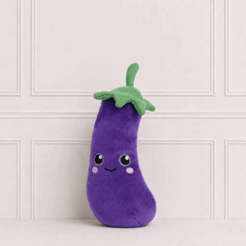 Soft purple eggplant plush toy with embroidered smiling face, rosy cheeks and green leafy top, displayed on a neutral background for décor.