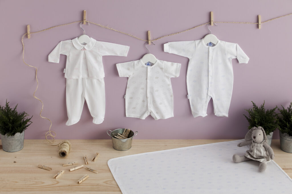Babidu baby clothing collection featuring classic Spanish outfits, babygrows and blankets beautifully displayed with soft toys in a nursery setting.