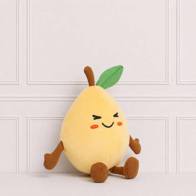 Soft yellow mango plush toy with embroidered smiling face, green leaf, brown stem and little arms and legs on a neutral background for décor.