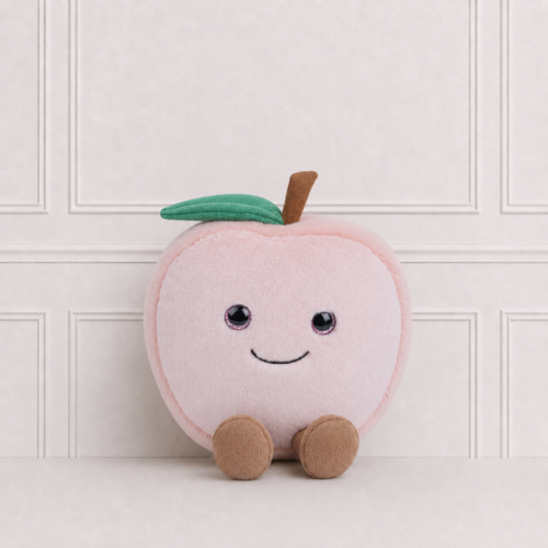 Soft pink smiling peach plush toy with green leaf and brown stem, sitting against a neutral background, perfect for nursery décor and cuddles.