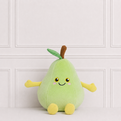 Cute pear plush toy with a smiling embroidered face, soft green fabric, yellow arms and feet, sitting on a white surface against a panelled backdrop.