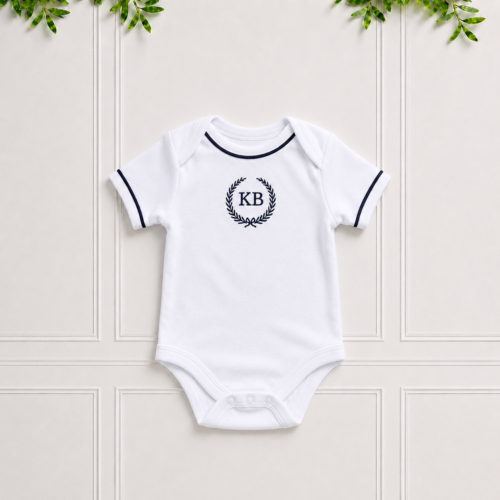 Navy baby vest in soft white cotton interlock with navy piping and elegant KB embroidery, perfect for newborn comfort and everyday wear.