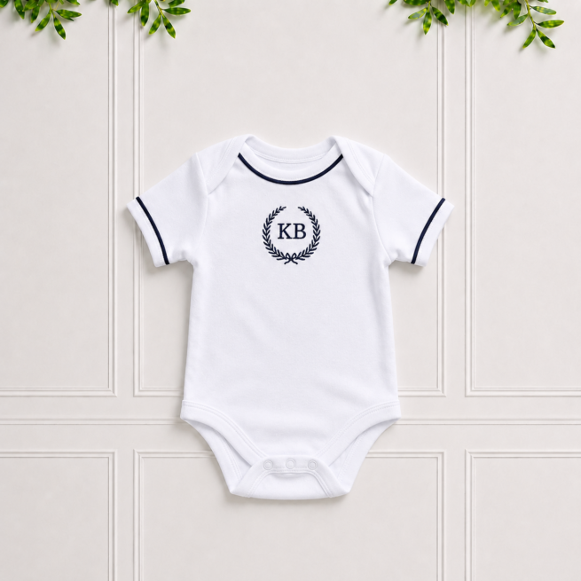 Navy baby vest in soft white cotton interlock with navy piping and elegant KB embroidery, perfect for newborn comfort and everyday wear.