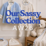 Sassy Baby AW26 collection with blue jacket, printed babygrow, blanket, bib and beanie displayed in a timeless nursery with teddy bear.