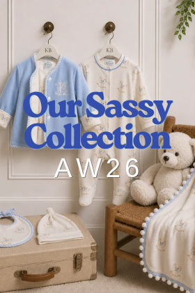 Sassy Baby AW26 collection with blue jacket, printed babygrow, blanket, bib and beanie displayed in a timeless nursery with teddy bear.
