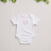 White baby vest in premium cotton interlock with soft pink piping, envelope neckline and elegant pink KB embroidery for everyday comfort.