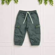 Green boys' cargo pants with elastic waistband, drawstring, cargo pockets and cuffed hems, displayed on a clean studio background with foliage.