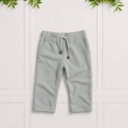 Soft sage green sweatpants with a ribbed waistband, drawstring, front pockets and rolled cuffs, displayed on a clean white paneled background.