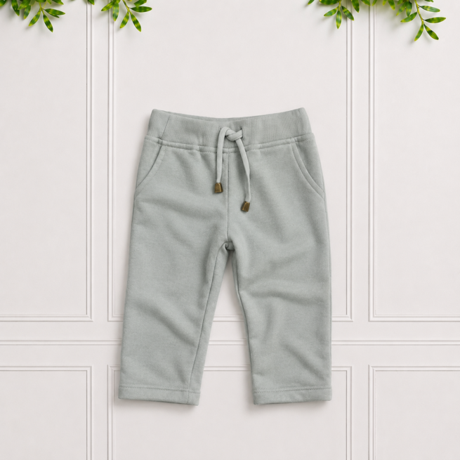 Soft sage green sweatpants with a ribbed waistband, drawstring, front pockets and rolled cuffs, displayed on a clean white paneled background.