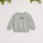 Soft sage green boys' crew neck sweatshirt featuring embroidered Koco Bino branding, ribbed cuffs and hem for a timeless casual look.