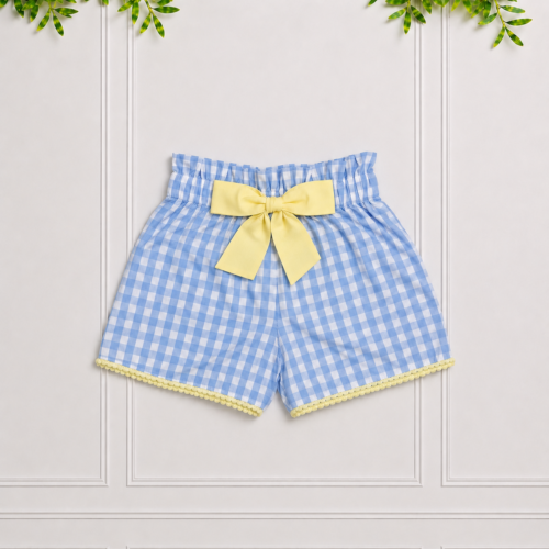 Girls' blue gingham shorts with a yellow bow and scalloped trim, photographed against a white panelled studio background.