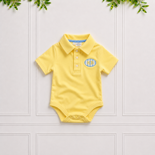 Yellow baby polo bodysuit with classic collar, short sleeves and KB embroidery, displayed against a white panelled background.