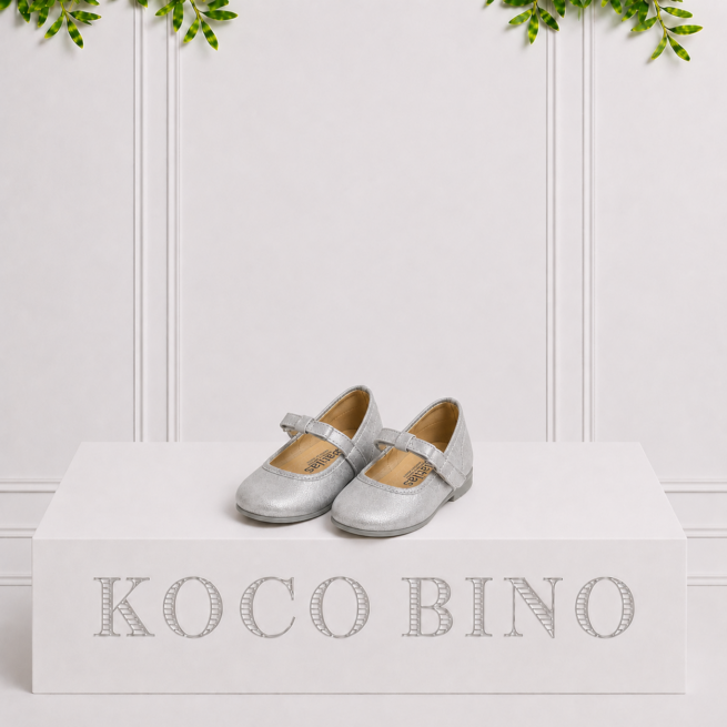 Silver girls party shoes with Mary Jane straps and a subtle shimmer, displayed on a Koco Bino pedestal for a stylish special occasion look.