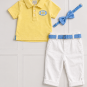 Flatlay of our Cooper Range for boys. It includes a yellow golfer, white linen pants, blue bow tie and belt.