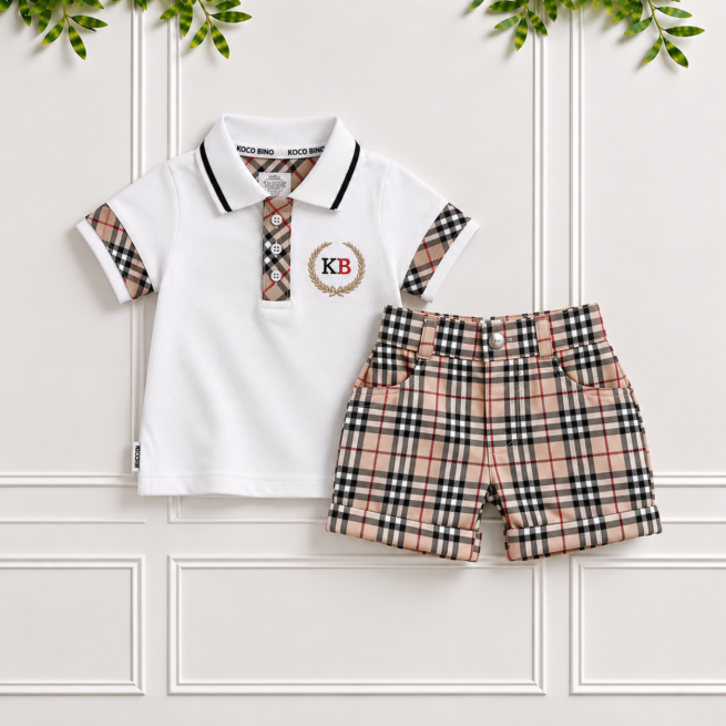 White boys check shorts paired with a matching polo shirt on a cream panelled studio wall, featuring a classic beige, black and red tartan.