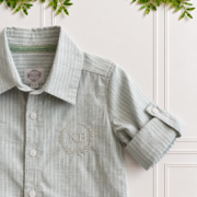 Close-up of boys sage green shirt showing striped cotton linen fabric, classic collar, roll-up sleeve and monogram embroidery.