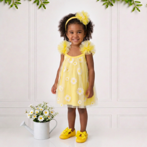 Young girl wearing a yellow daisy-print dress with floral shoulder details, yellow bow shoes and matching flower headband.