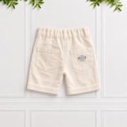 Boys cream linen shorts with back patch pockets, belt loops, elastic waistband and natural linen texture, displayed against a white panelled background.