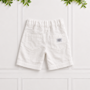 Boys white linen shorts with back patch pockets, belt loops, elastic waistband and natural linen texture, displayed against a white panelled background.