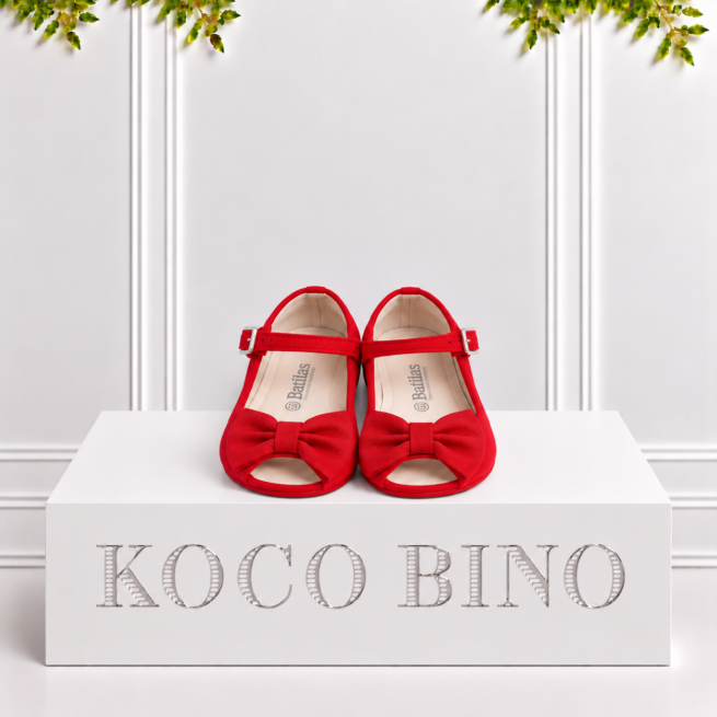 Bright red Batilas girls’ Mary Jane shoes with bows displayed on a white KOCO BINO pedestal in a stylish studio setting.